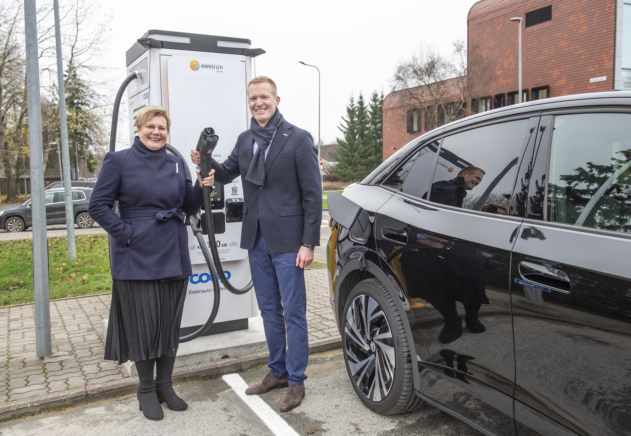 Coop Eesti Keskühistu juhatuse liige Veiko Haavapuu ja Elektrum Eesti tegevjuht Agnes Makk näitavad Jüri Konsumi juures värskelt avatud laadimisjaama, mis on osa Eesti suurimast jaeketi juurde rajatavast laadimisvõrgust. 